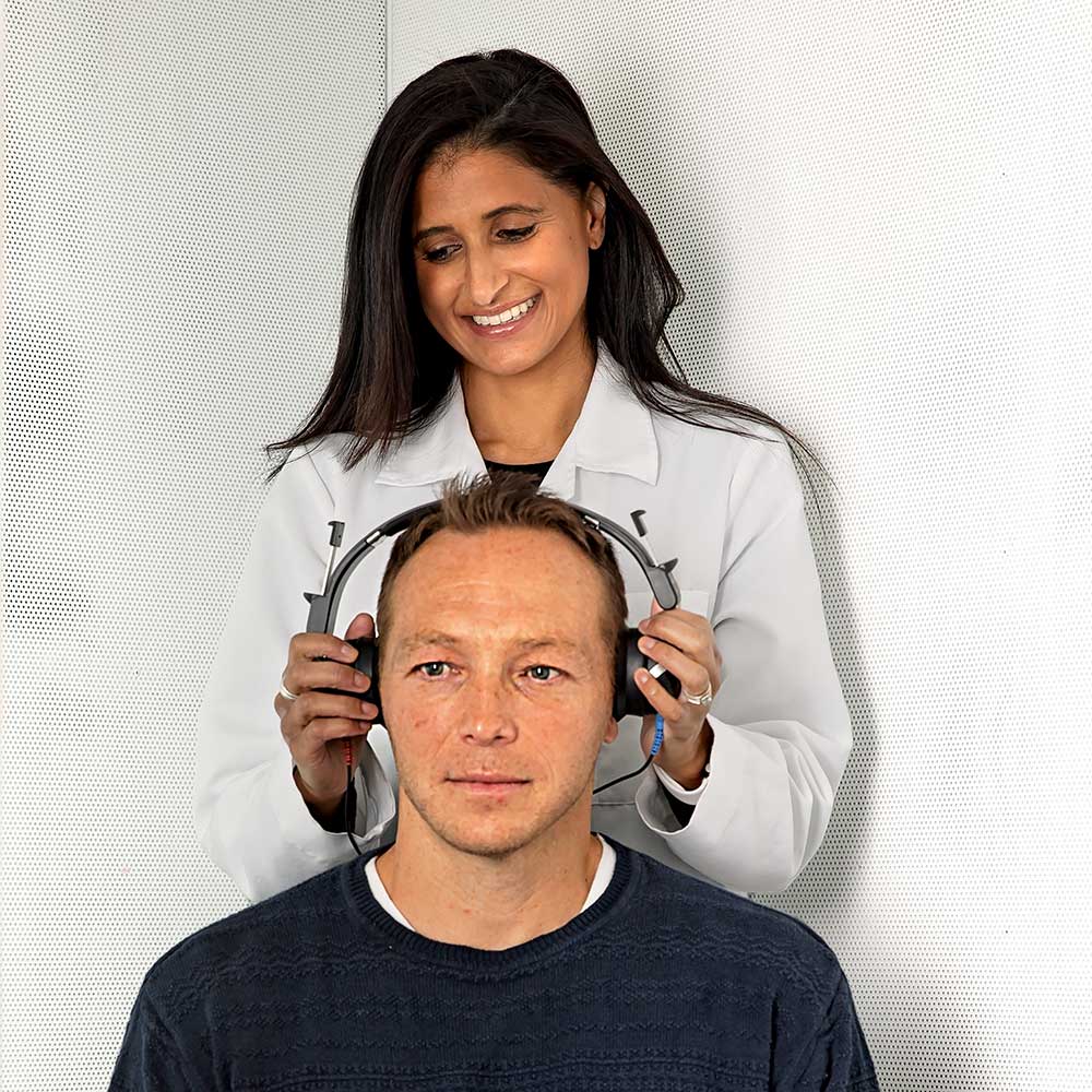 Audiologist putting headphones on a male patient during a hearing test